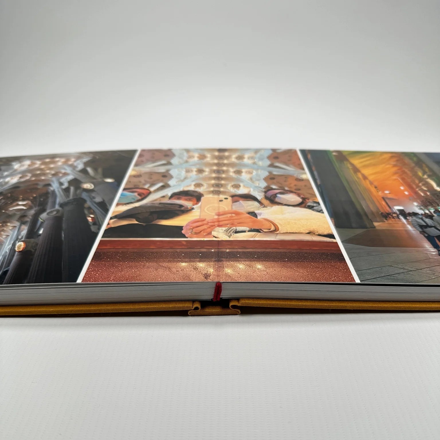 Fotolibro Premium Layflat abierto sobre una mesa, con fotografías a doble página y lomo cosido a mano