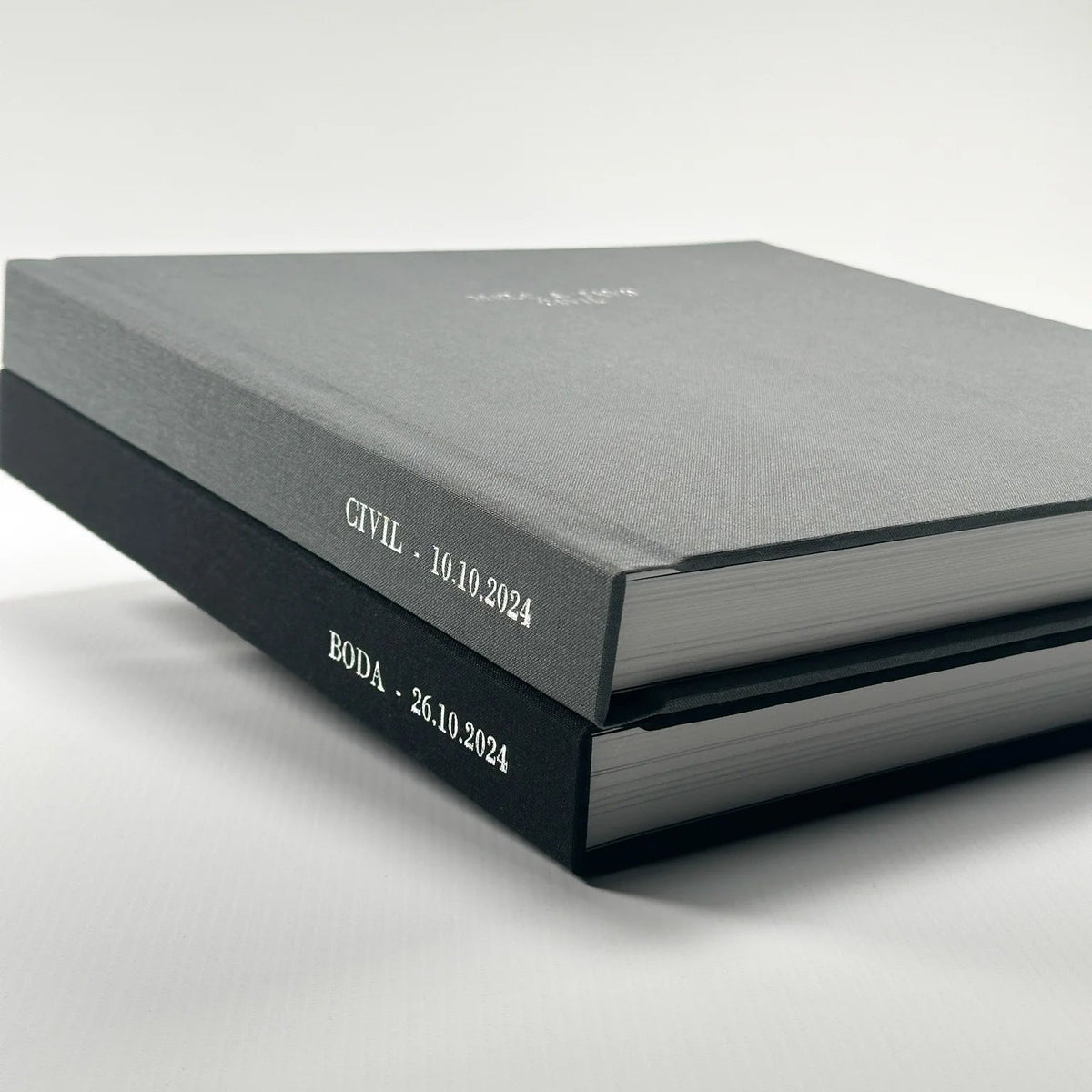 Dos Fotolibros Premium Layflat con tapa de lino gris y negro, personalizados con grabado en el lomo