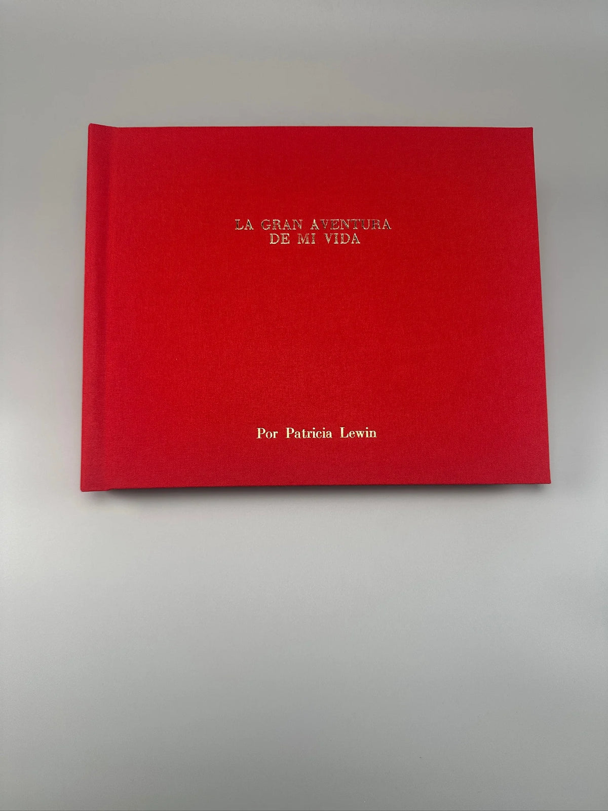Fotolibro apaisado con tapa de lino rojo y título personalizado en dorado, ideal como álbum de historias o regalo