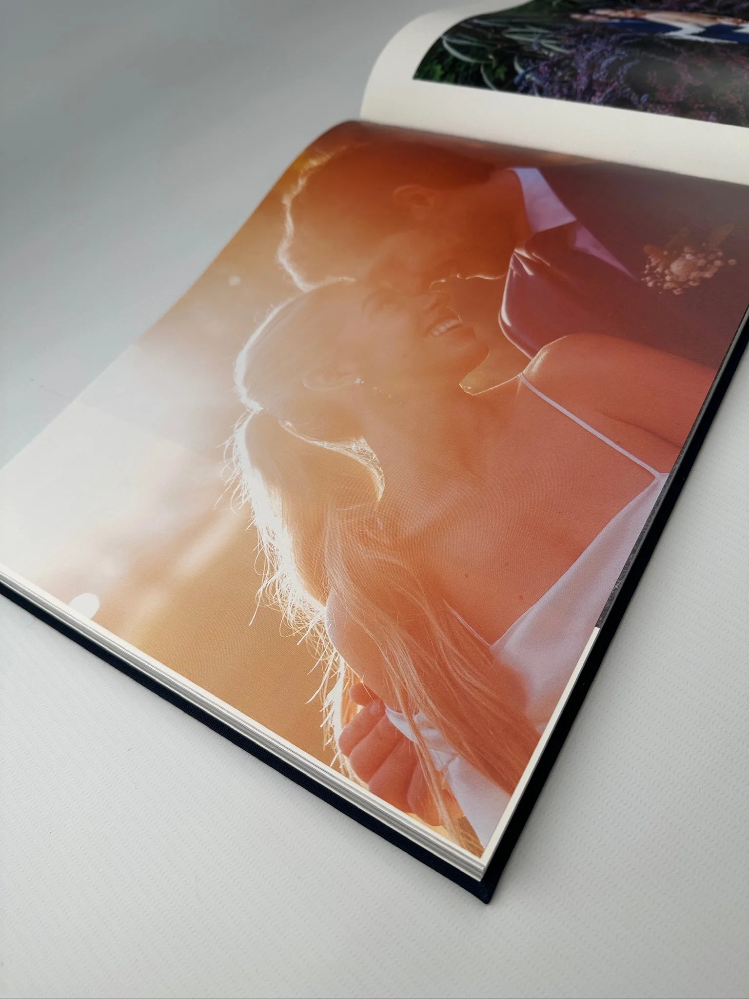 Fotolibro abierto con una foto de pareja a contraluz al atardecer impresa a página completa sobre papel mate texturado