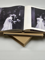 Dos fotolibros de tapa de lino beige, uno abierto a doble página con fotos de boda en blanco y negro