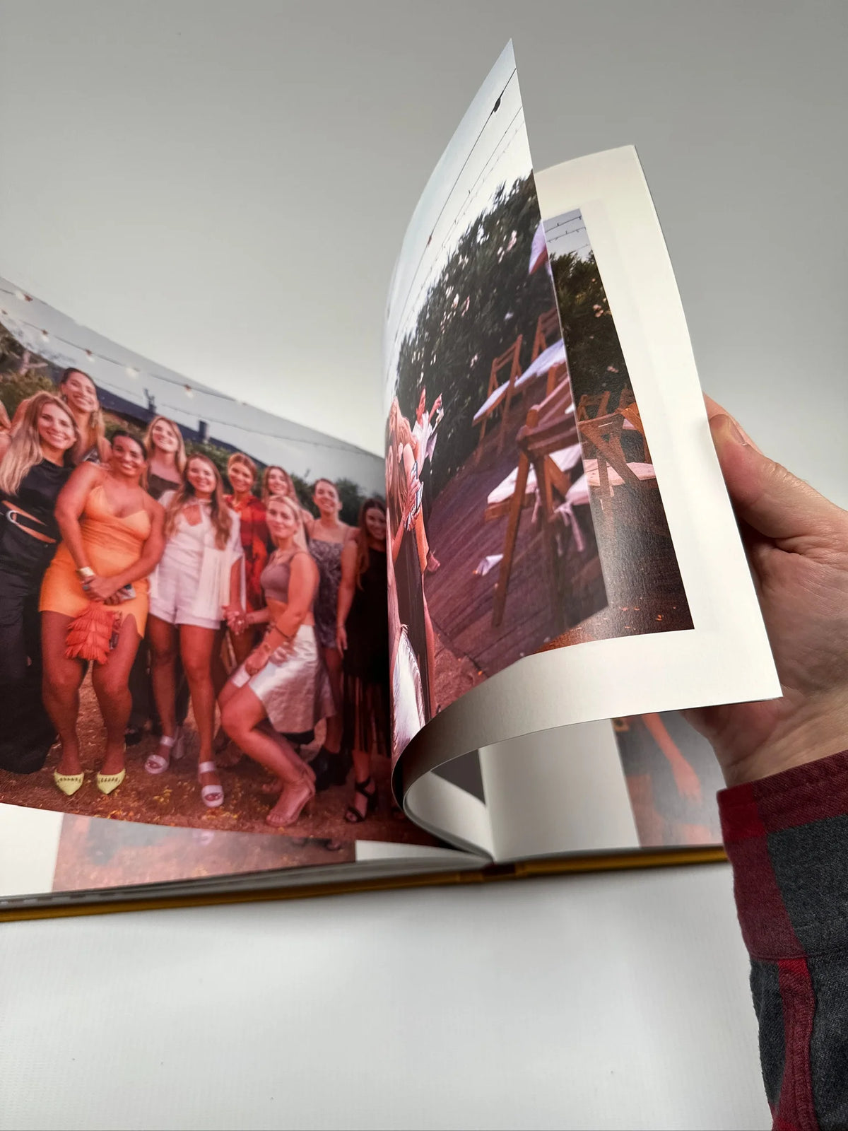 Fotolibro abierto con apertura layflat de 180° y una foto de grupo de amigas en una fiesta impresa a doble página sin corte central