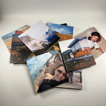 Varios fotolibros cuadrados desplegados en abanico con fotos de paisajes y momentos familiares en la tapa