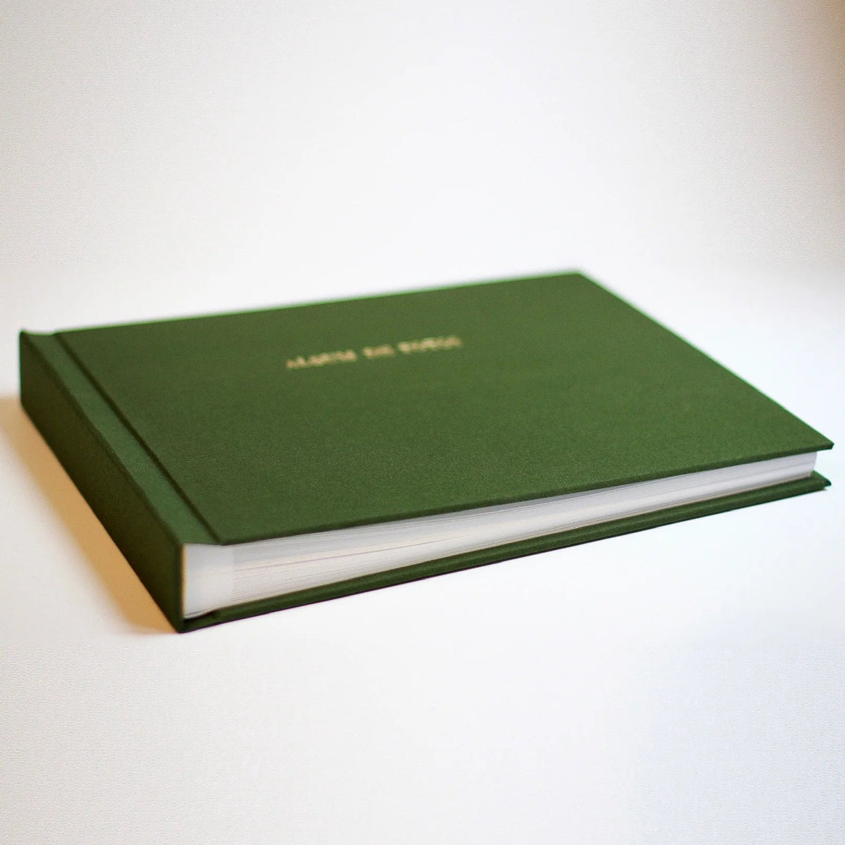 Álbum de fotos apaisado con tapa de lino verde y nombre grabado en dorado sobre fondo claro
