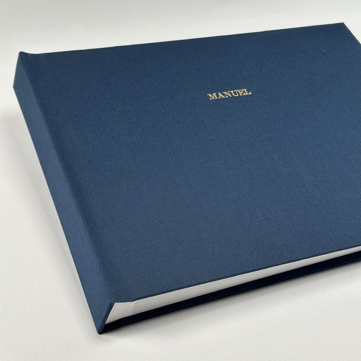 Álbum de fotos apaisado con tapa de lino azul marino y el nombre Manuel grabado en dorado
