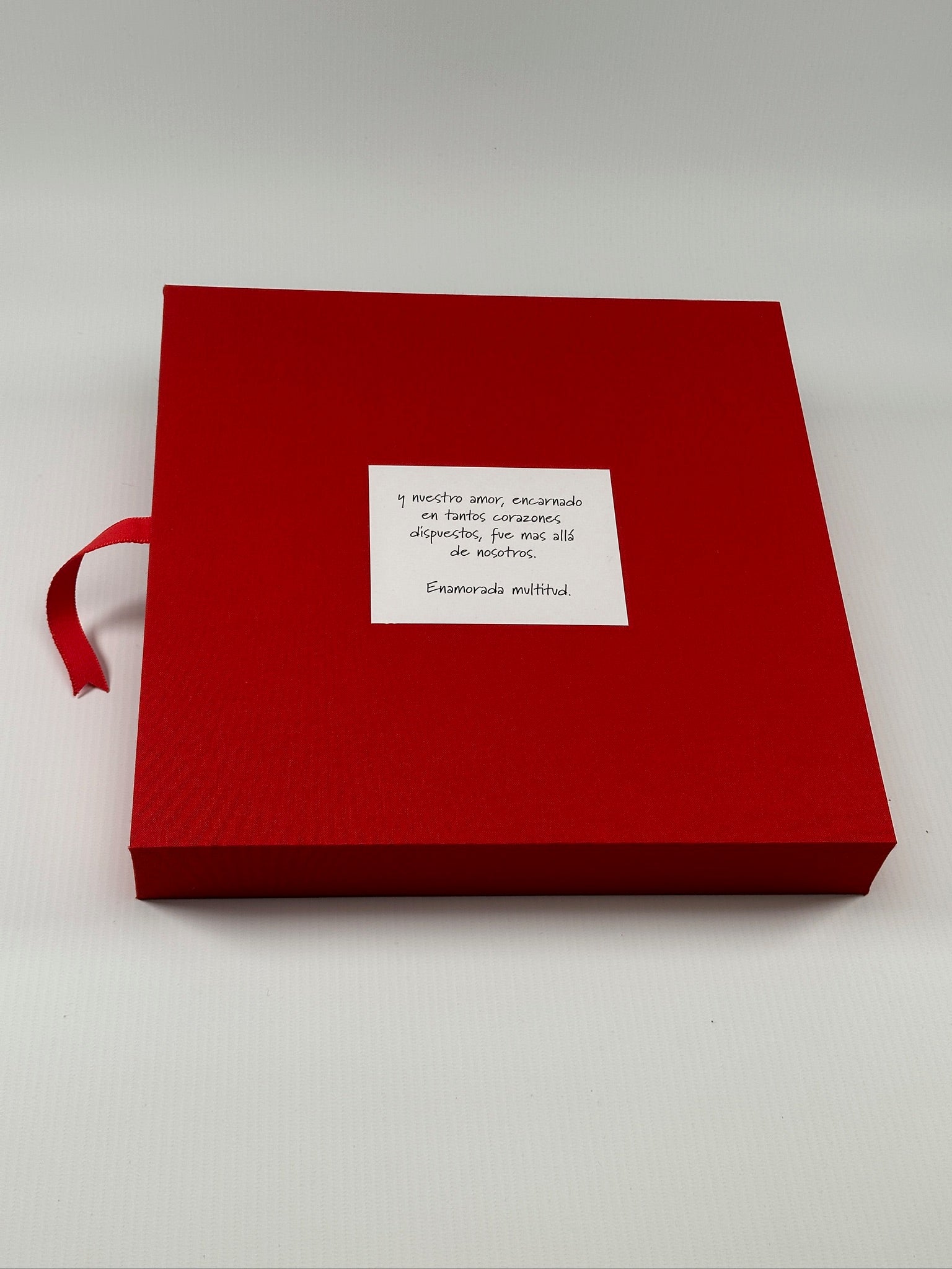 Tapa del estuche de lino rojo con la tarjeta de dedicatoria centrada y la cinta de apertura