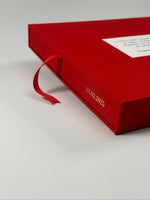 Detalle del canto del estuche rojo con la fecha grabada en dorado y la cinta de tela roja