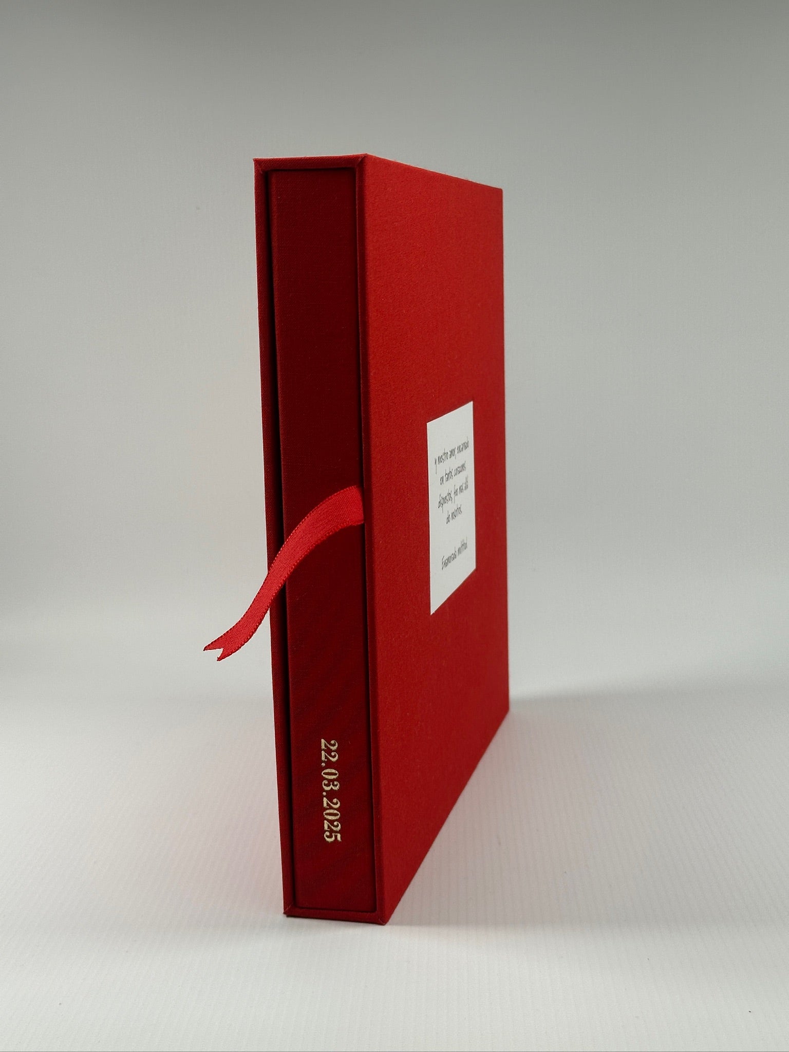 Estuche de lino rojo de pie de canto, con dedicatoria al frente y la fecha grabada en el lomo