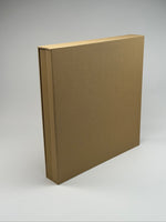 Estuche apaisado de lino camel de canto, con el fotolibro de hojas gruesas asomando adentro