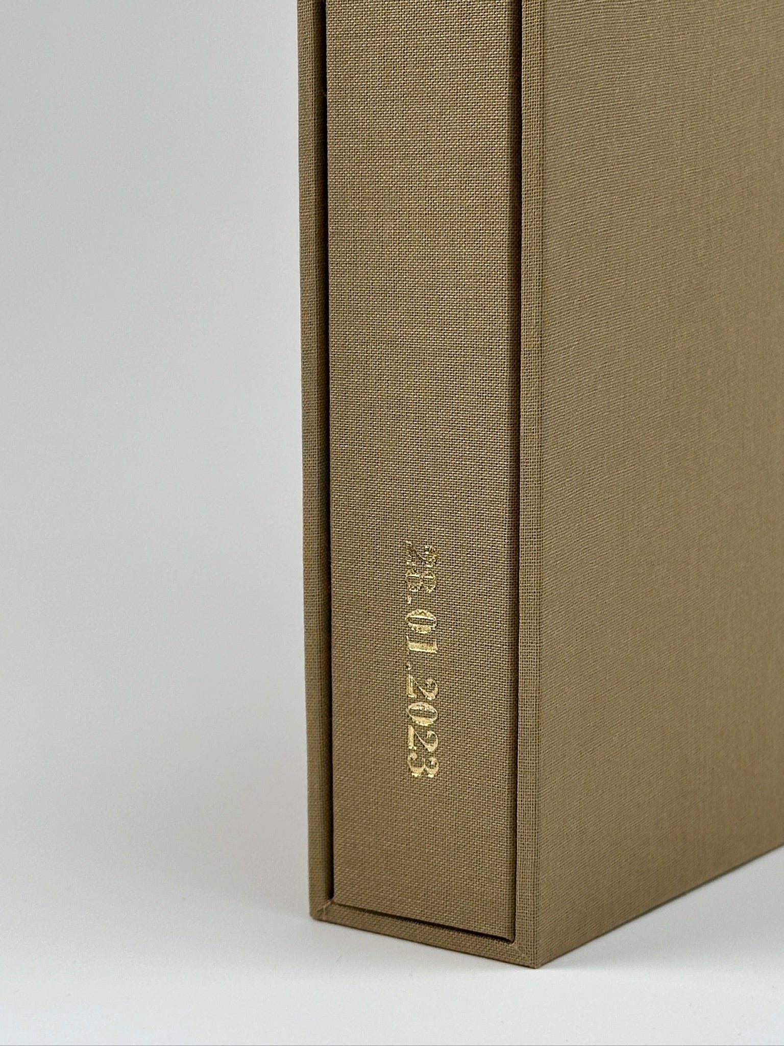 Detalle del álbum camel asomando del estuche de lino, con nombre grabado en dorado