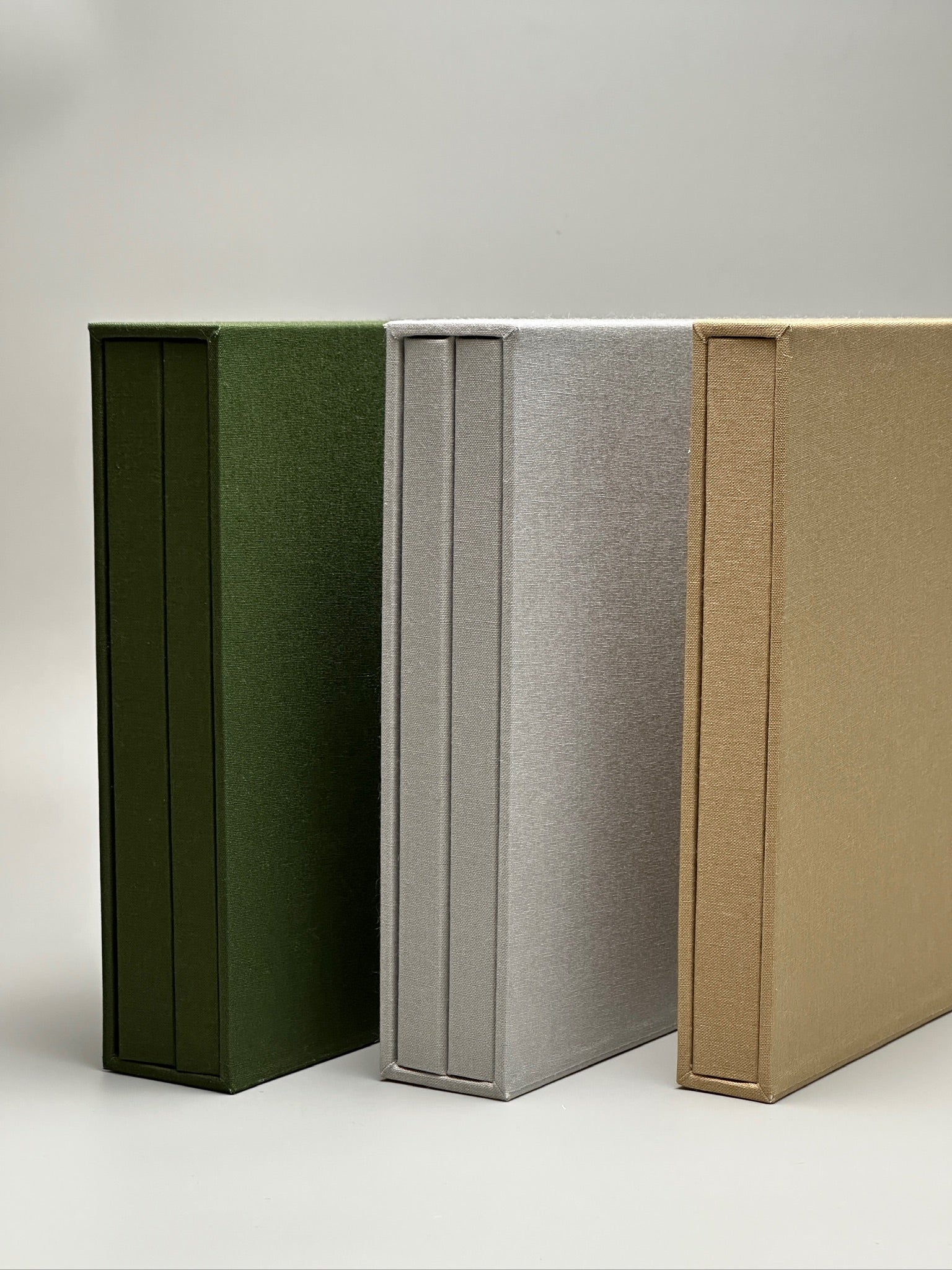 Estuches de lino verde, gris y avena de canto, mostrando la textura del lino en cada color