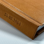 Detalle del lomo de cuero color cognac con la fecha 26.08.1964 grabada en Hot Stamping